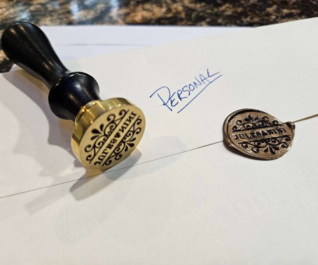 A brass wax seal pressed onto a Jules and Nini envelope, with handwritten "Personal" notation